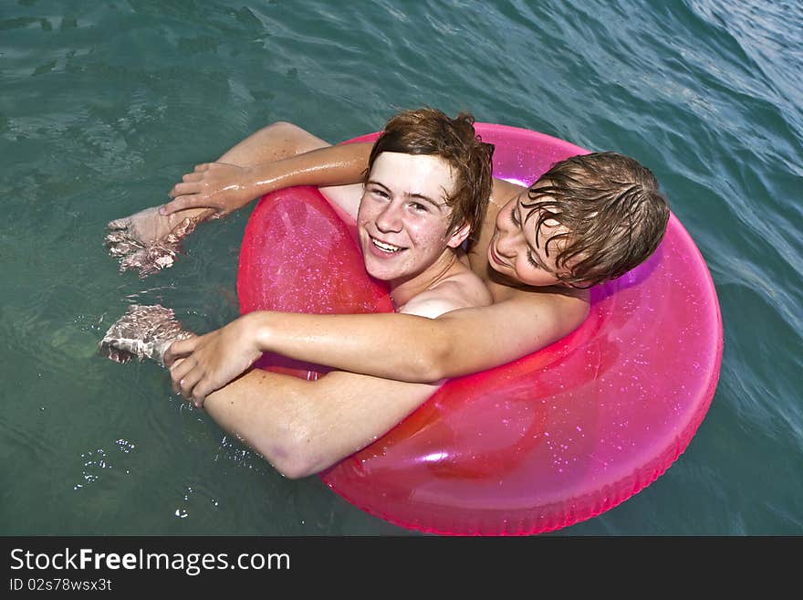 Two brothers in a swim ring have fun in the ocean