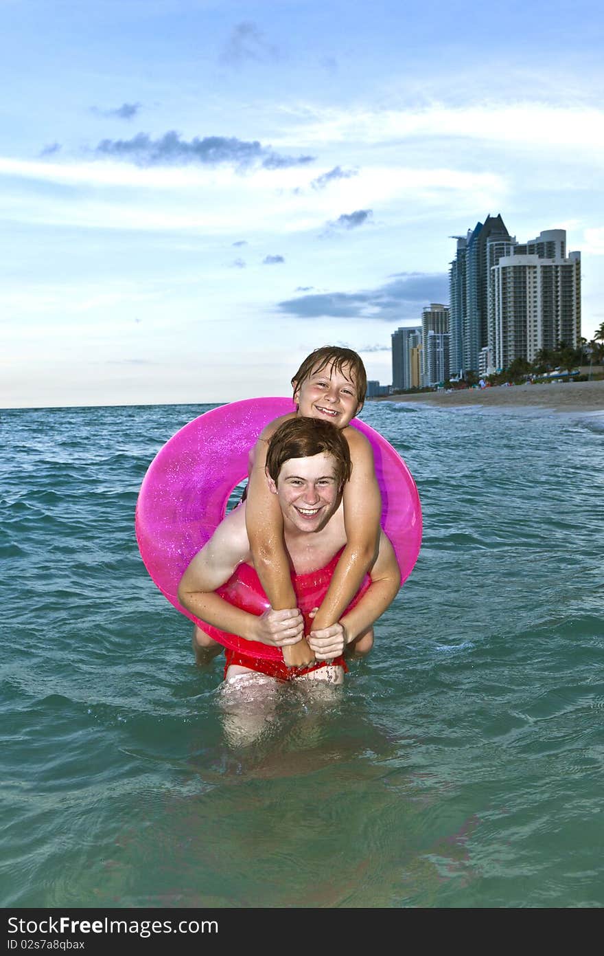 Two brothers in a swim ring have fun in the ocean