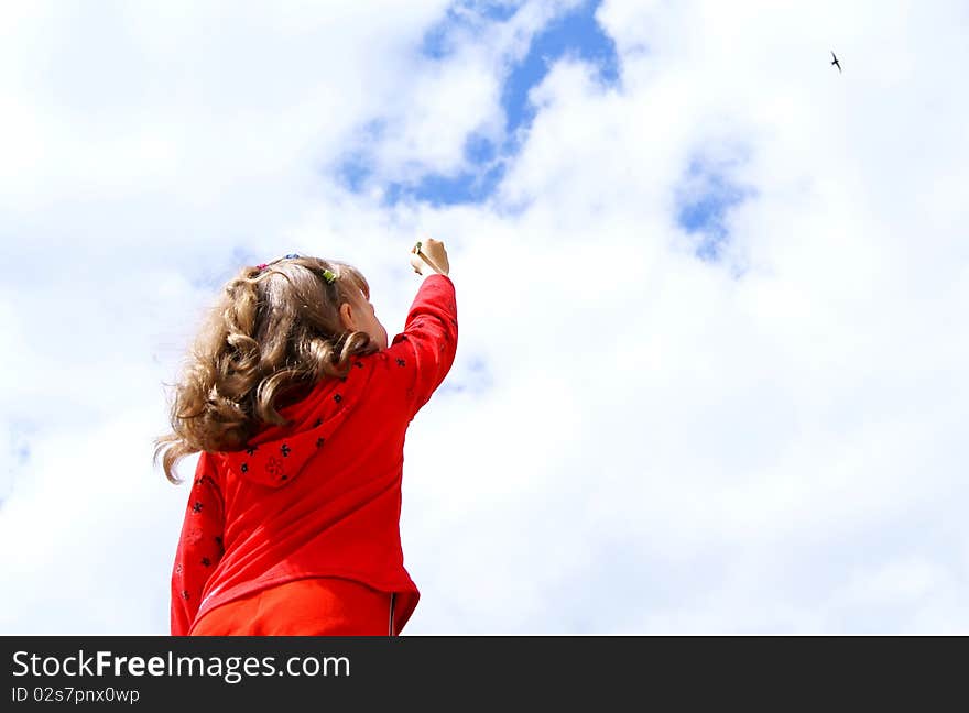 The child in red clothes draws a pencil in the sky with clouds. The child in red clothes draws a pencil in the sky with clouds