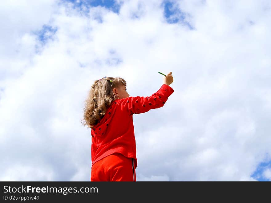 The girl in red clothes draws a pencil in the sky with clouds. The girl in red clothes draws a pencil in the sky with clouds