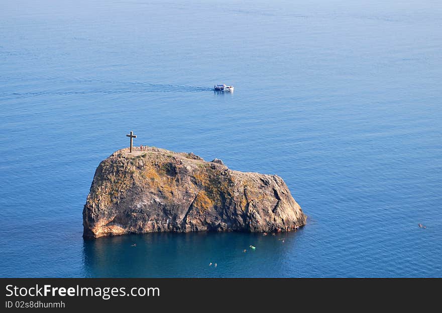 Wooden cross standing on a rock on the middle of the sea. Wooden cross standing on a rock on the middle of the sea.