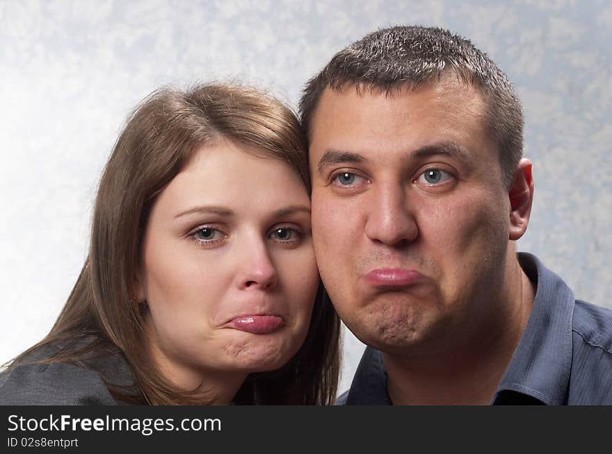 Young upset couple over light defocused background looking one at another. Young upset couple over light defocused background looking one at another