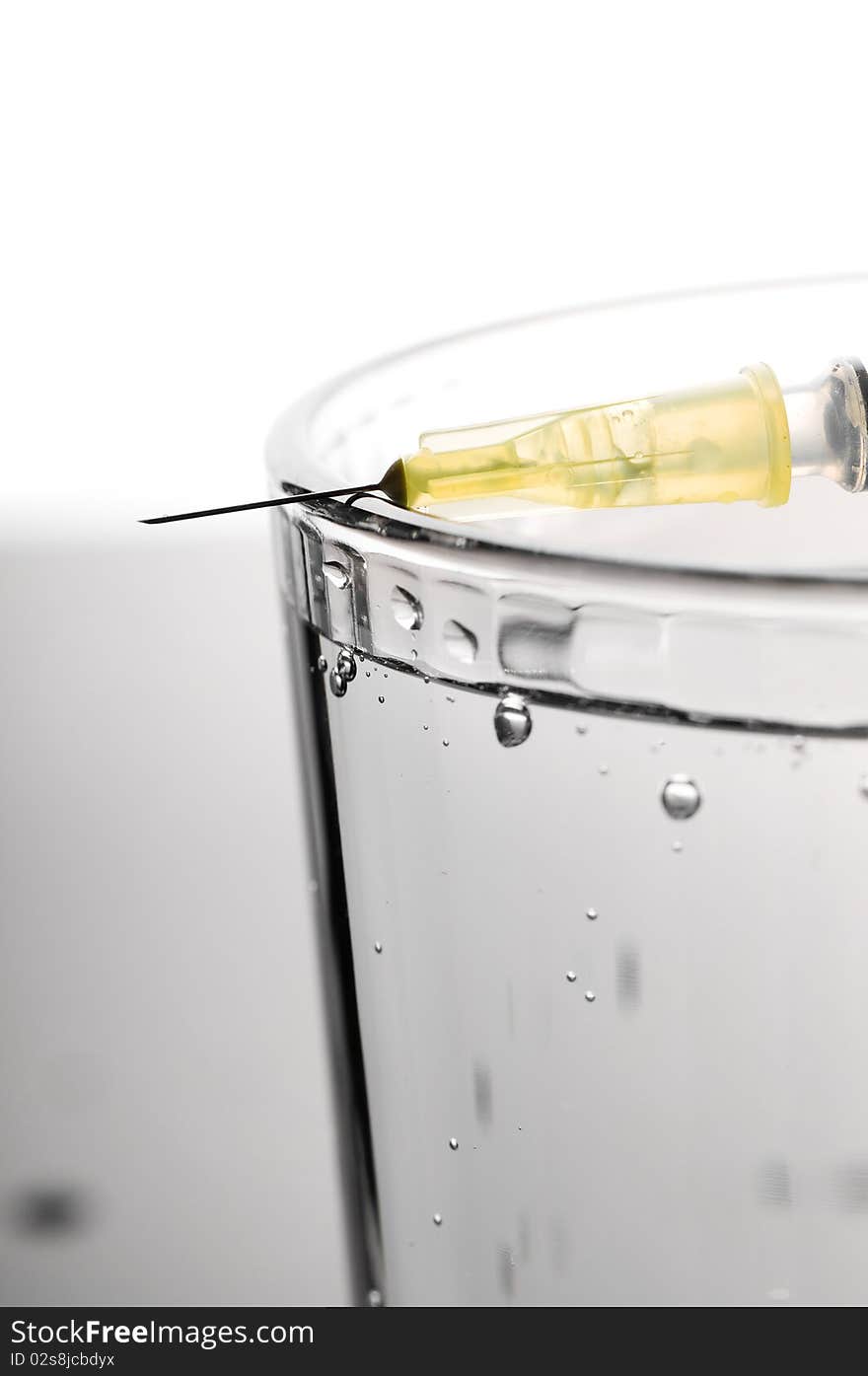 Water test. Glass with water and syringe with a needle.