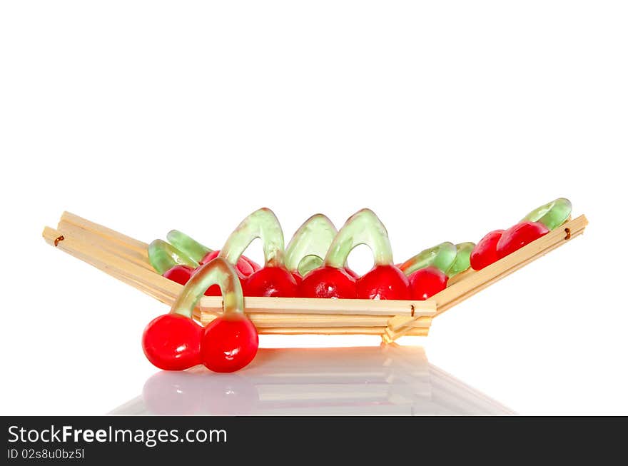 Candy in the form of sweet cherries in a wooden tray isolated over white. Candy in the form of sweet cherries in a wooden tray isolated over white