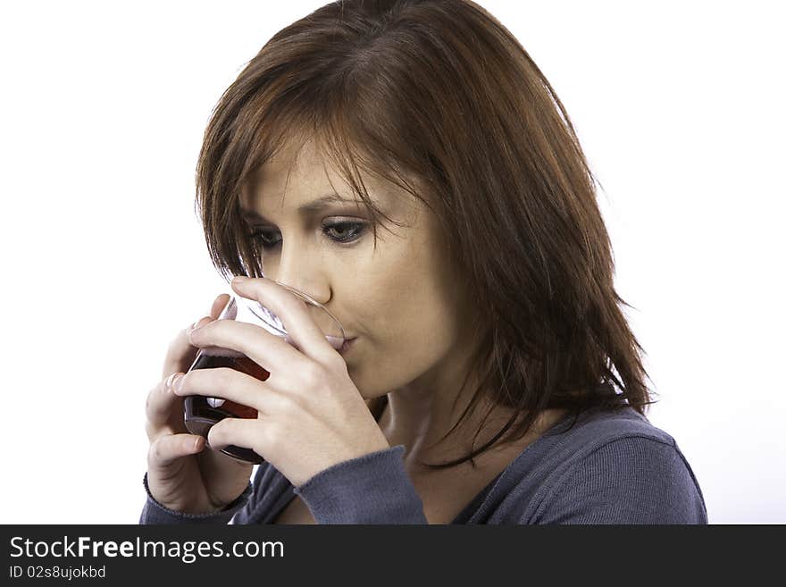 A beautiful young woman with red hair drinking a red fizzy drink from a glass. A beautiful young woman with red hair drinking a red fizzy drink from a glass