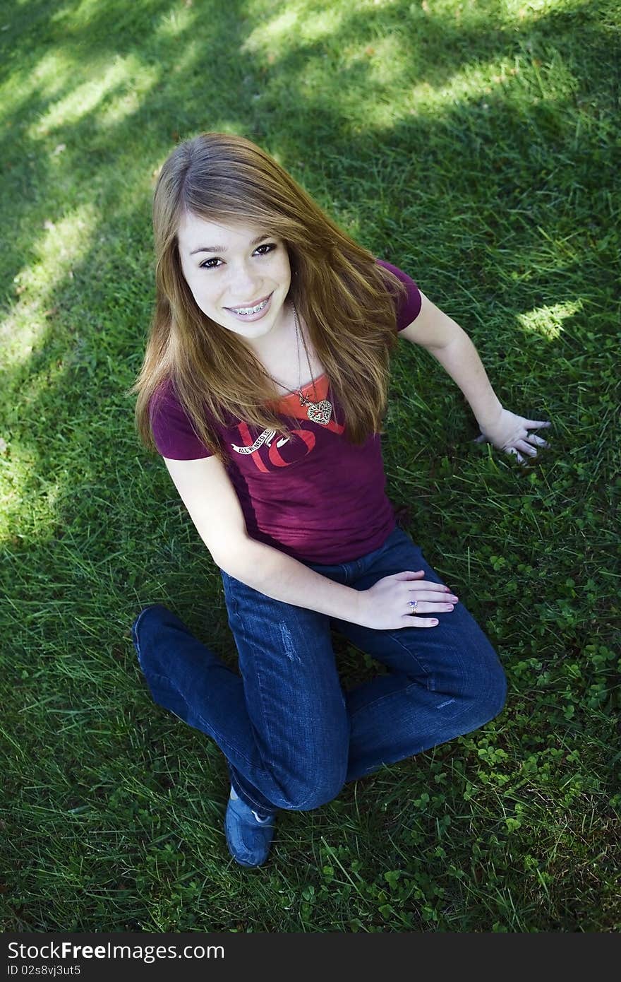 Teenage girl sitting in the grass looking up. Teenage girl sitting in the grass looking up