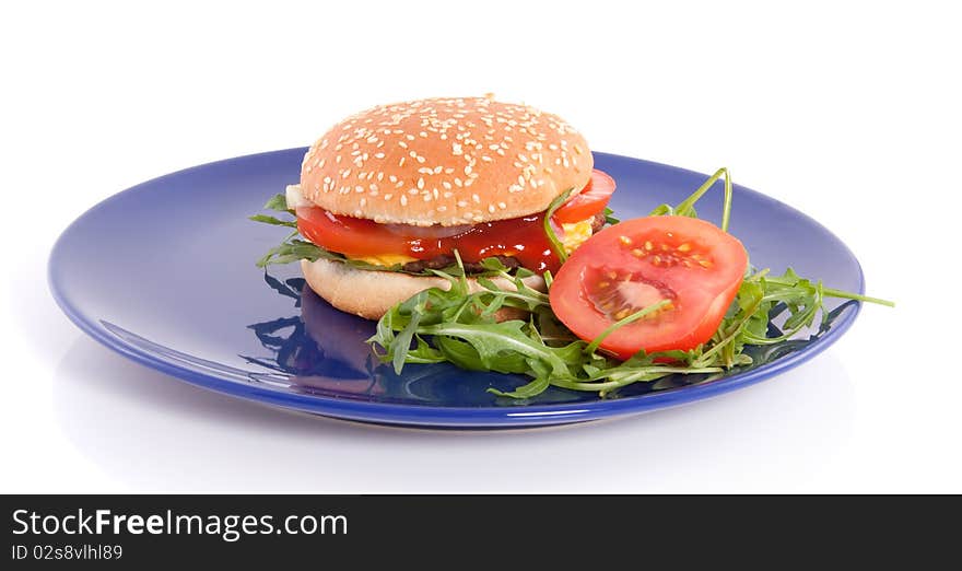 A close-up of a a fresh hamburger with cheese and salad on a blue plate  isolated over white. A close-up of a a fresh hamburger with cheese and salad on a blue plate  isolated over white