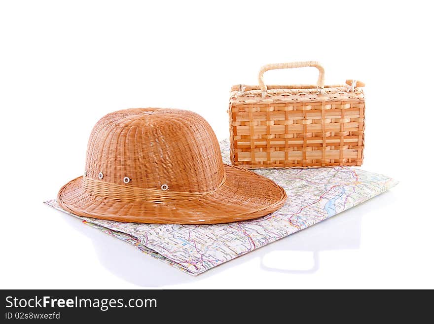 A straw hat and a wicker trunk on a map isolated over white. A straw hat and a wicker trunk on a map isolated over white