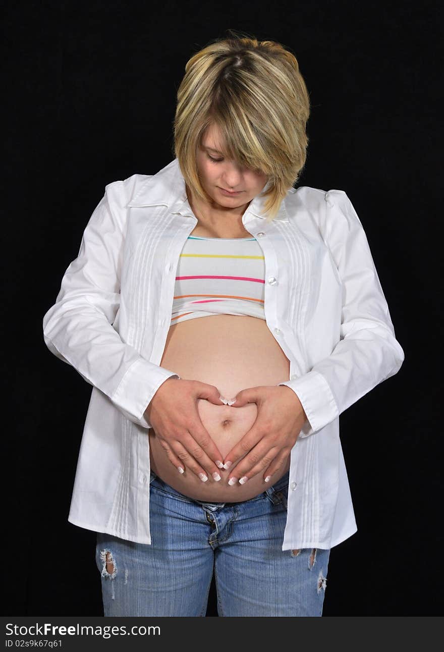 Mother-to-be holding heart made by hands in front of belly