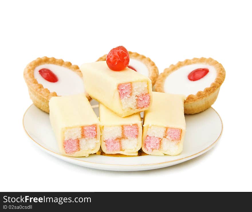 Plate with delicious cakes, cupcakes and cherry on top. Isolated over white background. Plate with delicious cakes, cupcakes and cherry on top. Isolated over white background.