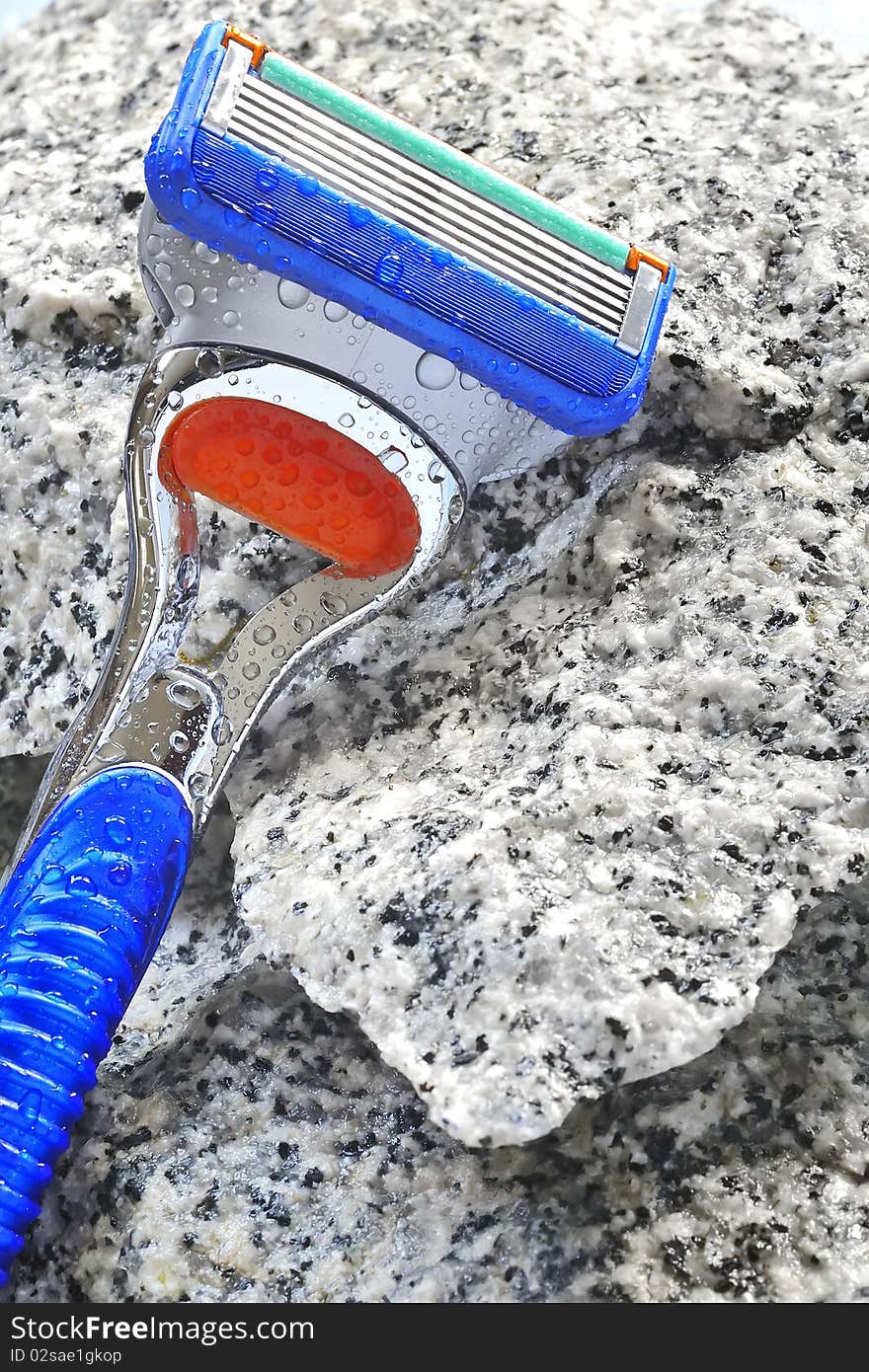 Razor on stone background with water drops in studio