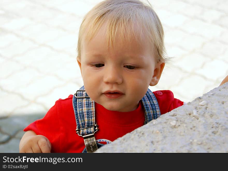 The little boy attentively examines something during walk. The little boy attentively examines something during walk