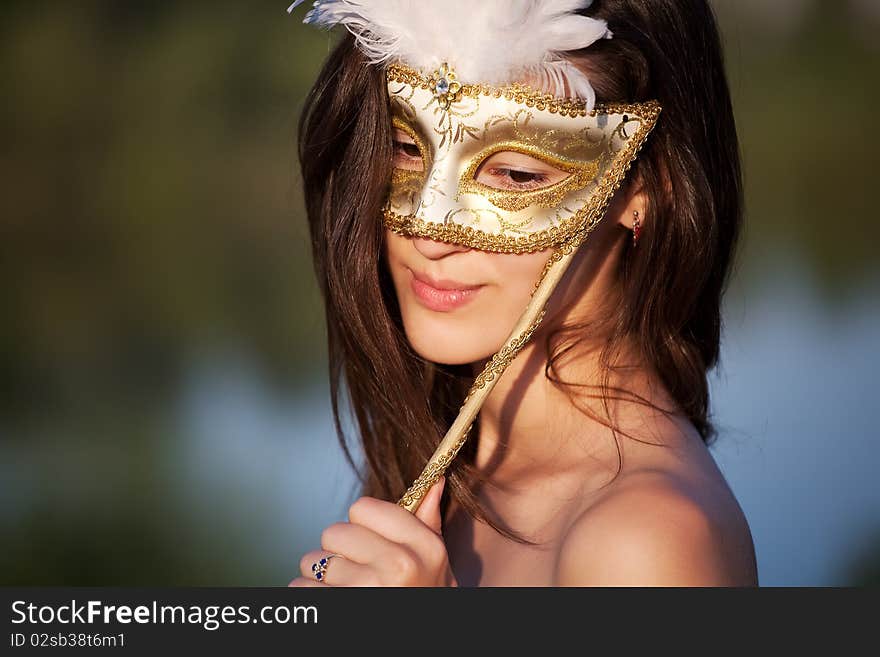 Beautiful woman in carnival mask over outdoor background