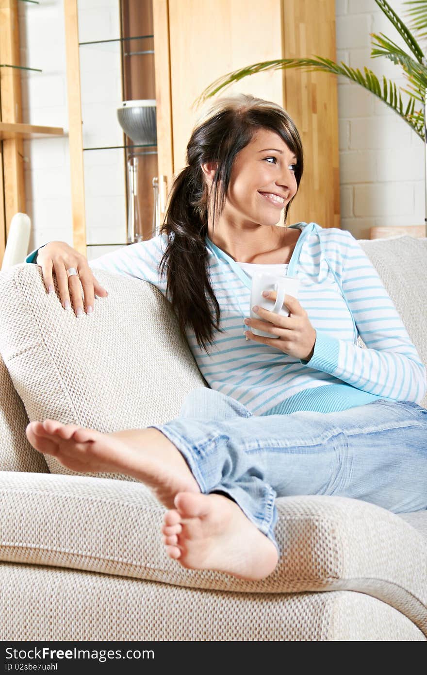 Woman in living room with coffee is smiling. Woman in living room with coffee is smiling