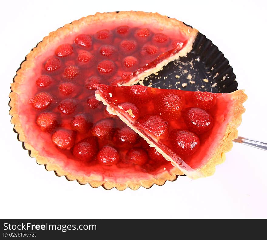 Strawberry Tart in a tart pan with a slice of it cut out on a white background