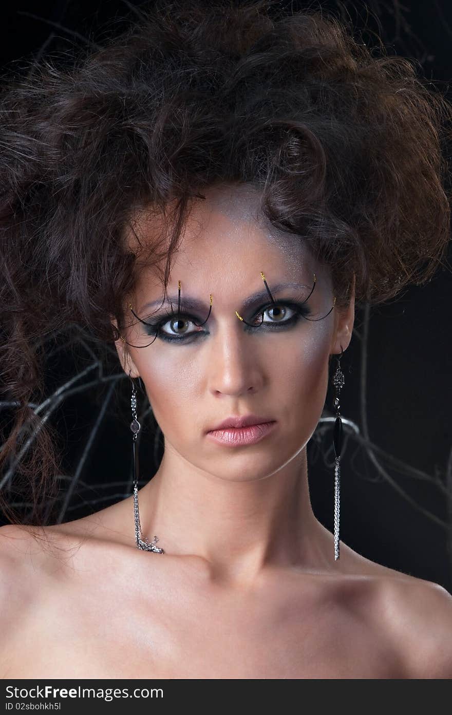 Fashion portrait of a young woman in makeup. The image is taken on a dark background.