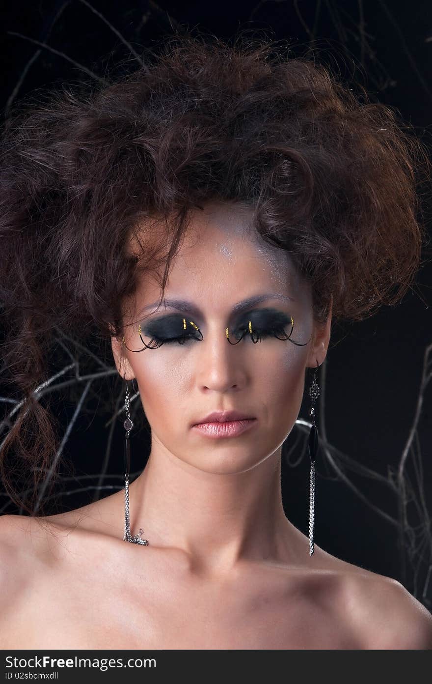 Fashion portrait of a young woman in makeup. The image is taken on a dark background.