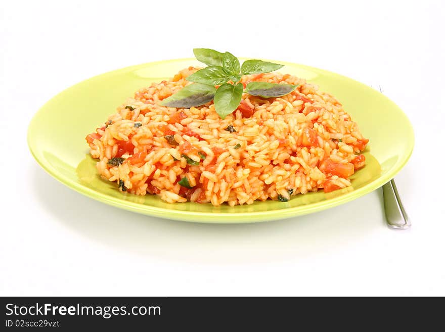 Risotto with tomatoes on a green plate decorated with basil