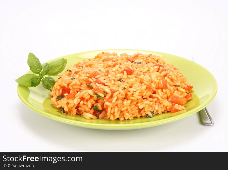 Risotto with tomatoes on a green plate decorated with basil