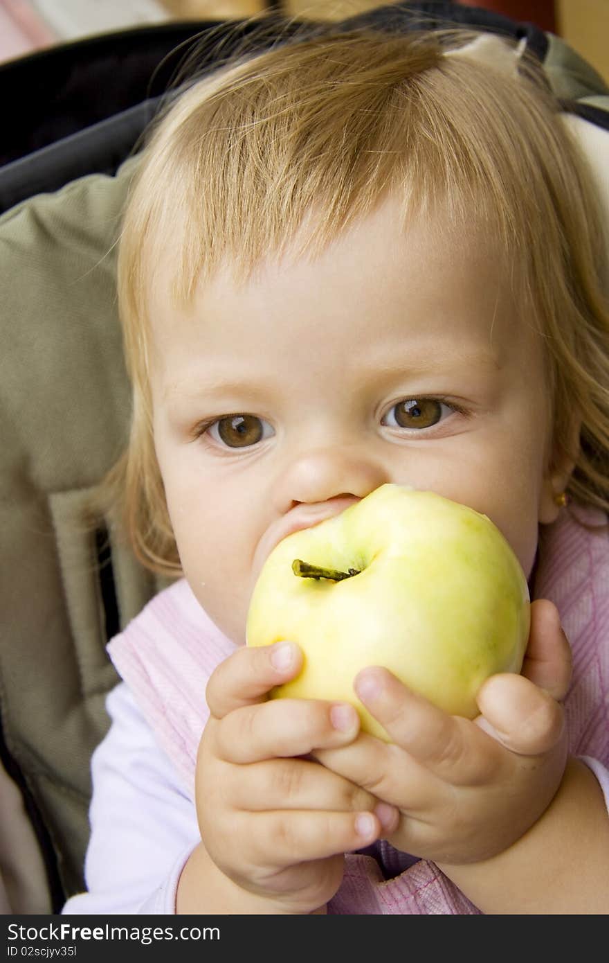 Small child bites the big apple and holds its two hands