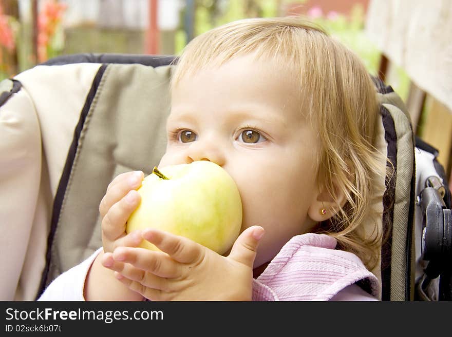 Small child bites the big apple and holds its two hands