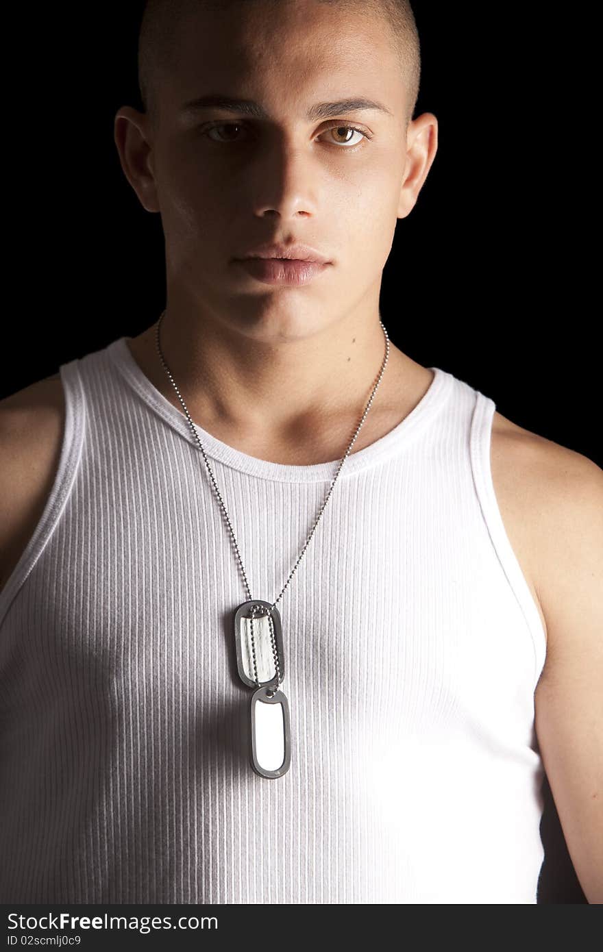 A good looking, muscular built, man on a black background with dog tags. A good looking, muscular built, man on a black background with dog tags.