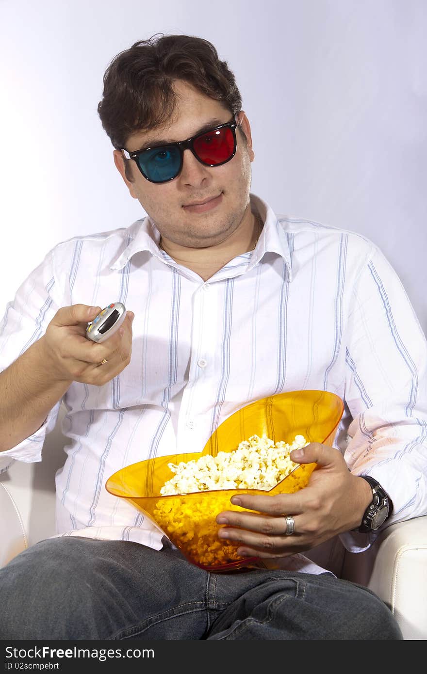 A young man watching a movie in 3D, with stylish 3D glasses and eating popcorn. A young man watching a movie in 3D, with stylish 3D glasses and eating popcorn.