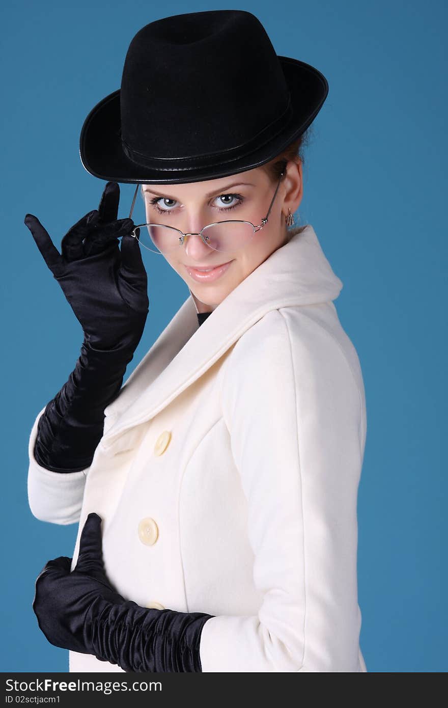 Young woman in a black hat smiles and looks over his glasses. Young woman in a black hat smiles and looks over his glasses