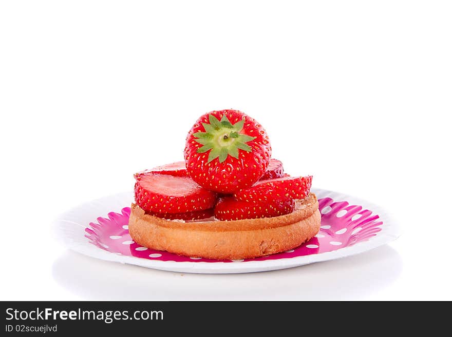 A biscuit with strawberries on a pink dotted plate, isolated over white