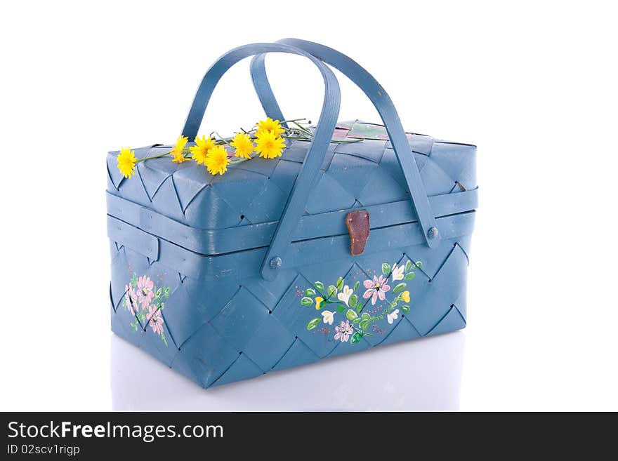 A blue wicker basket decorated with yellow daisies isolated over white background