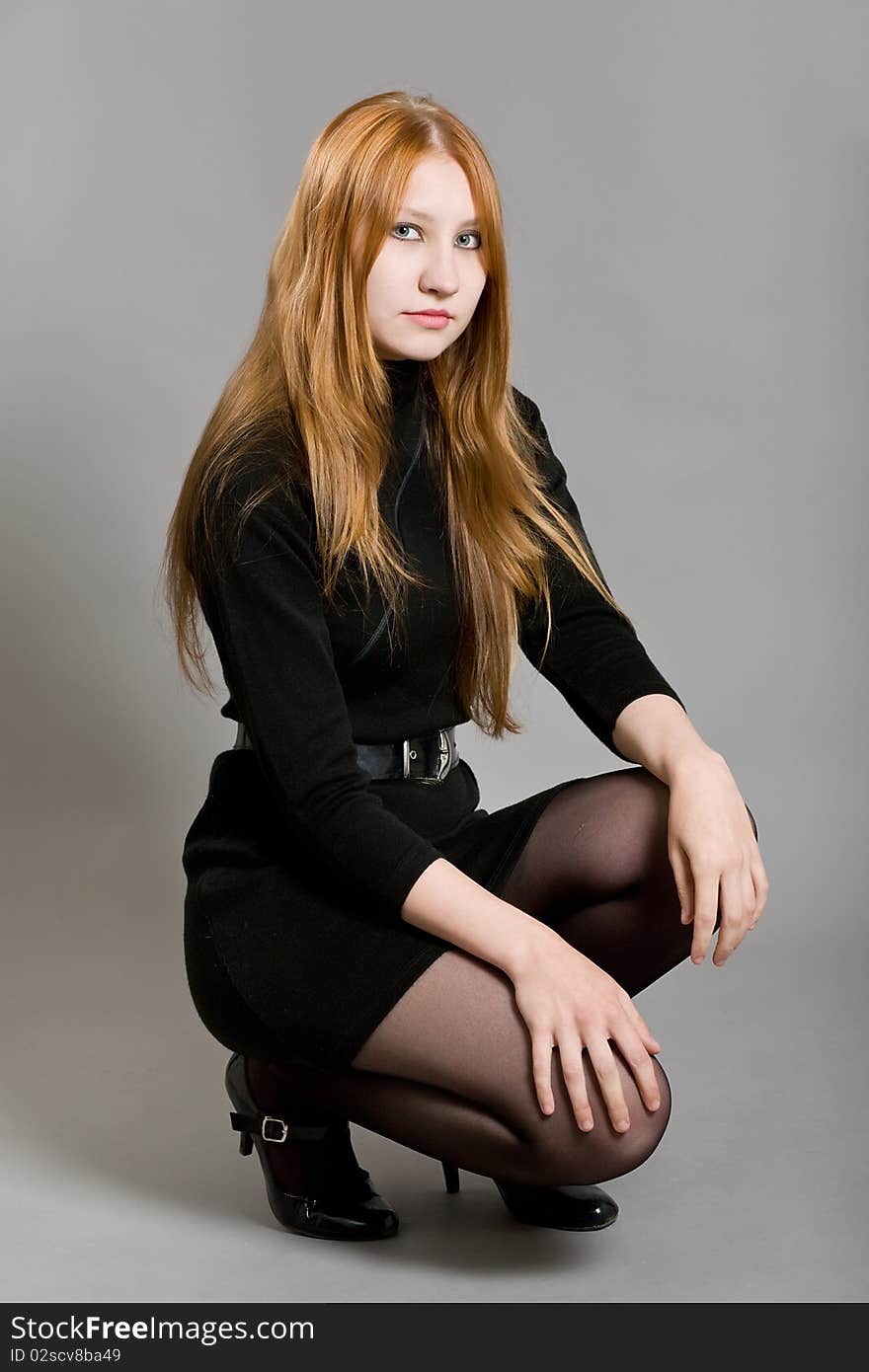 Young attractive girl in a black dress on a gray background. Young attractive girl in a black dress on a gray background