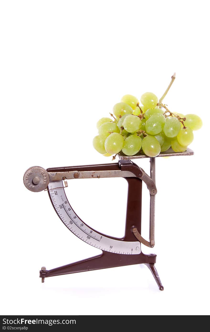 An antiqueted scale with white grapes on top isolate dover white