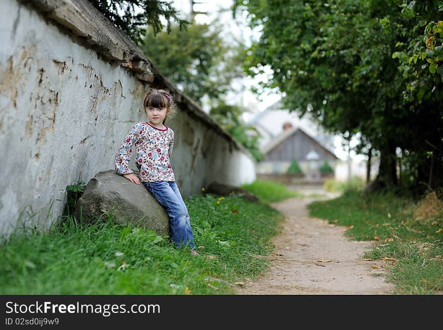 Nice toddler girl near the wall  on country road