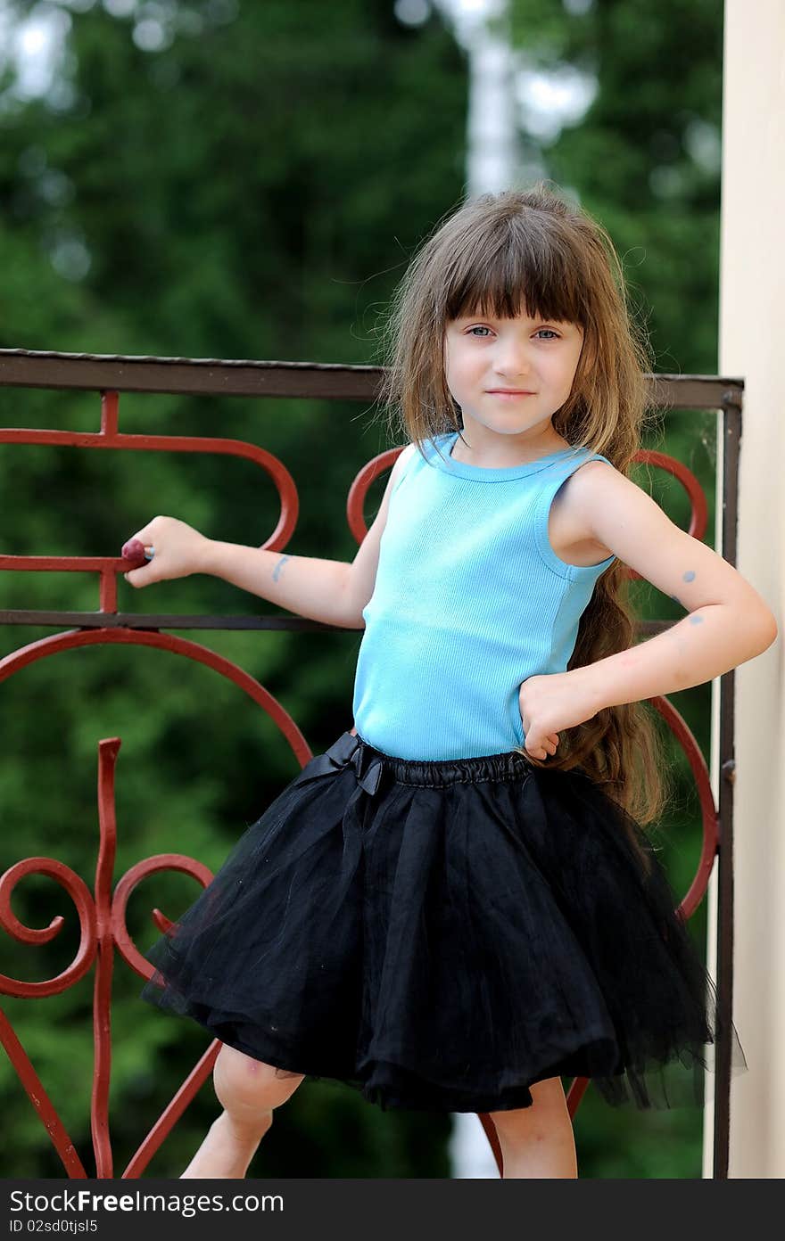 Adorable toddler girl with very long dark hair on the balcony in tutu skirt