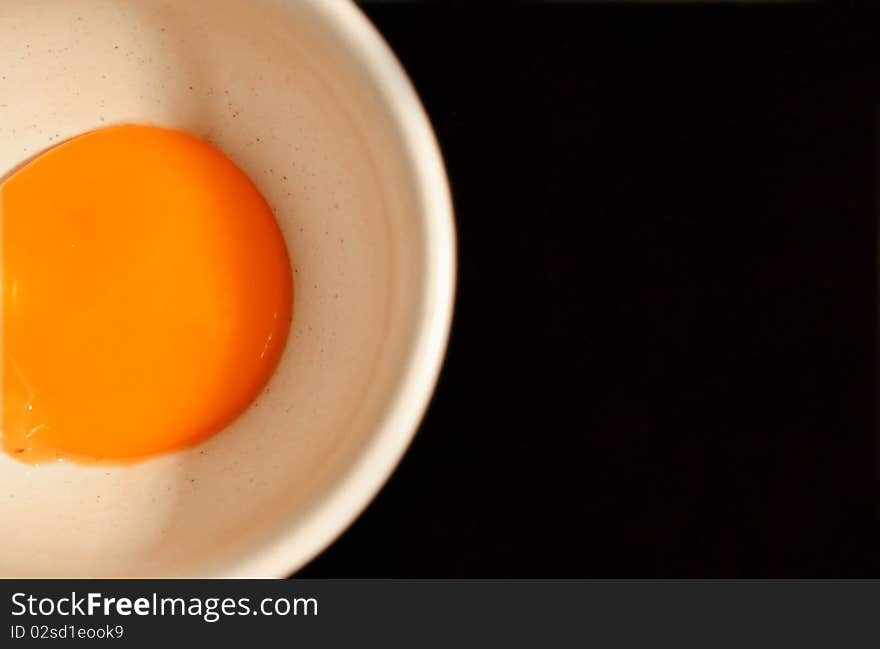 Egg's yolk in white cup on black background. Egg's yolk in white cup on black background.