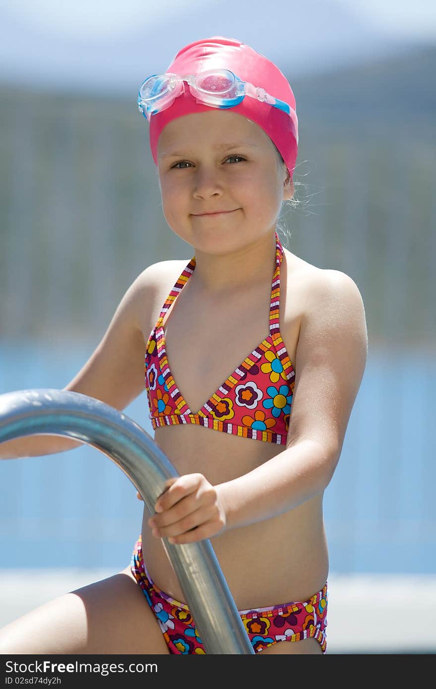 Little child in bathing cap, glasses on pool stair