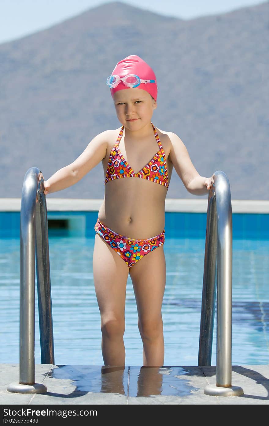 Little girl in bathing cap, glasses walks up stair