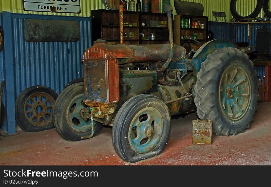 Rusty old tractor sitting in the corner of an old 1930 style garage. Rusty old tractor sitting in the corner of an old 1930 style garage