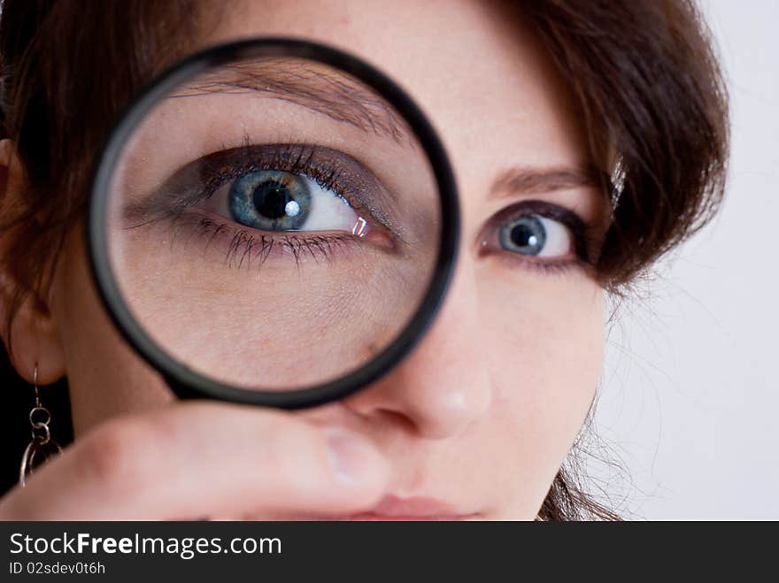 Girl's eye magnified through magnified glass on white