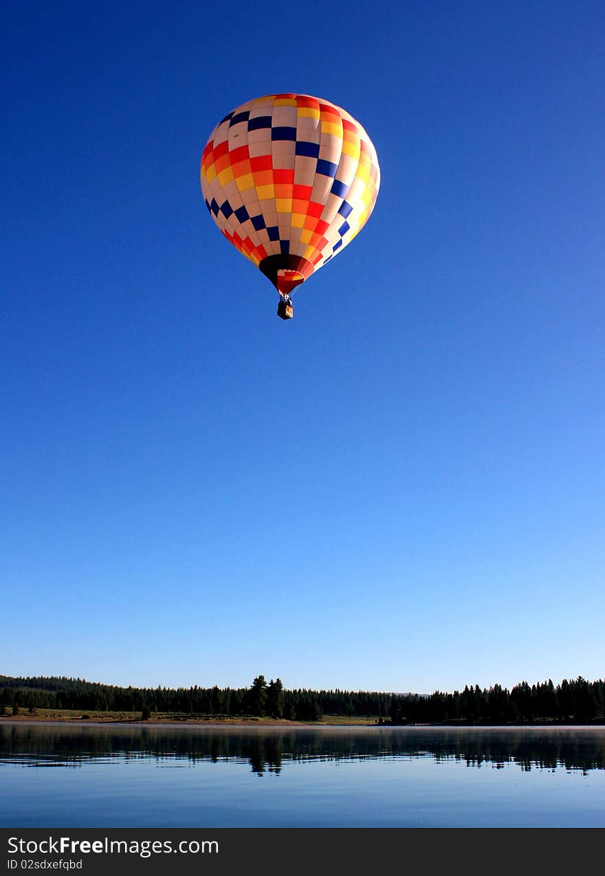 A hot air balloon floats over a calm lake. A hot air balloon floats over a calm lake