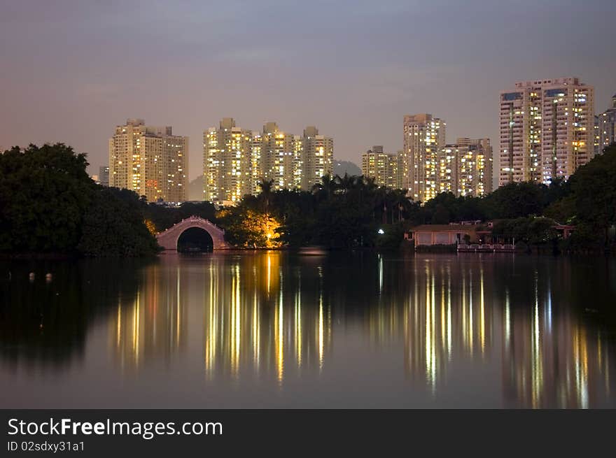 Lake park by night, Leeche Park in Shenzhen city, China. Evening landscape with reflections in water and small bridge.