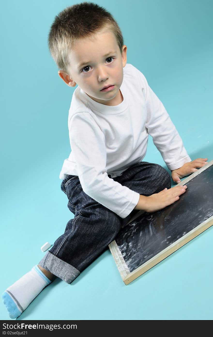 Little boy playing with chalk on black board