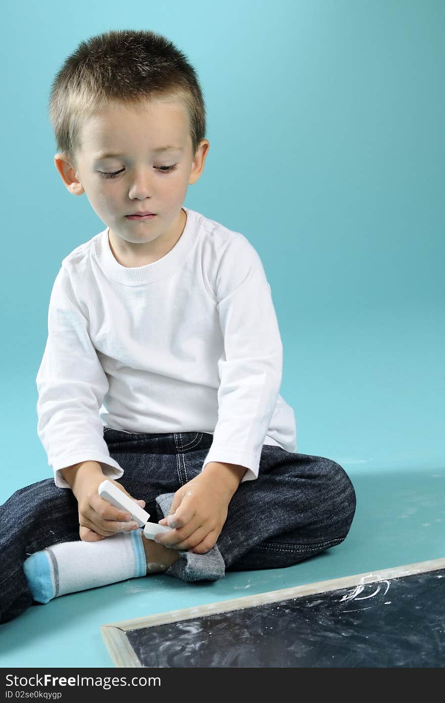 Little boy playing with chalk on black board