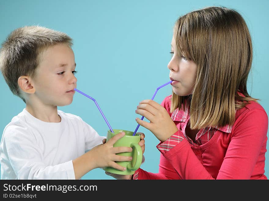 Two white children sharing cup with juice