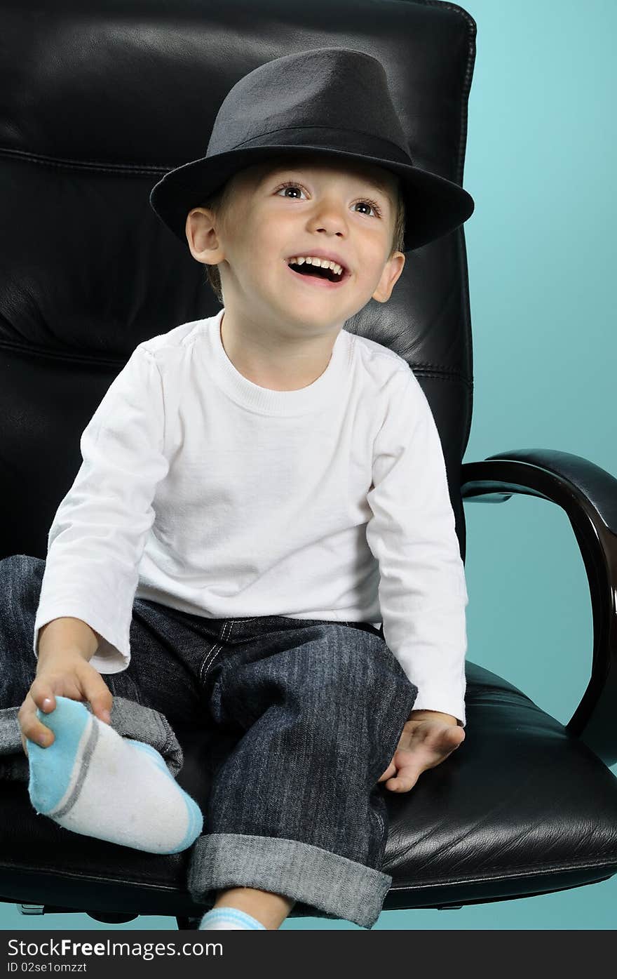 Photo with one child sitting on chair in studio and showing black accessory. Photo with one child sitting on chair in studio and showing black accessory