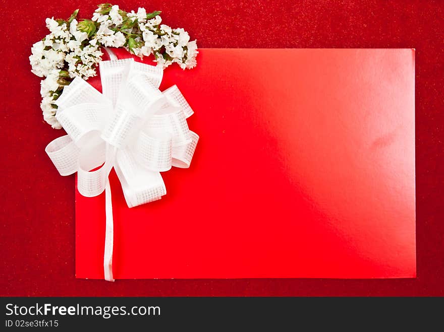 Greeting card with bow and flowers on red background. Focus on bow