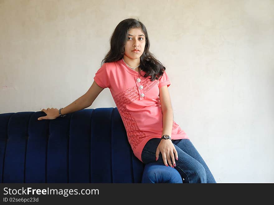 A young Indian woman sitting in her home.