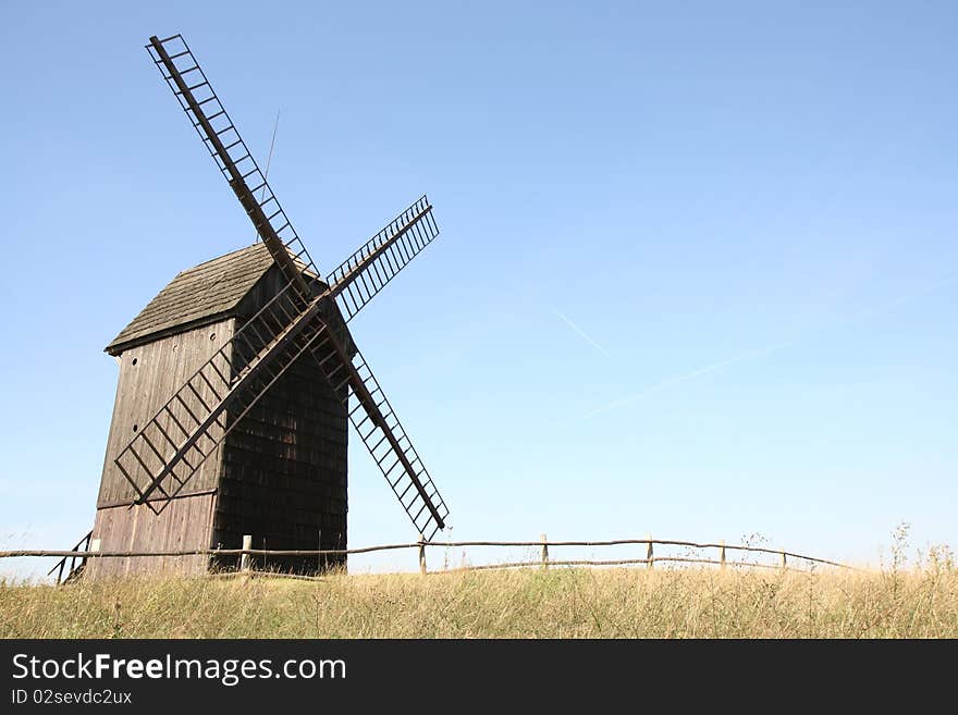 Old windmill (trestle type) in a field with a fence