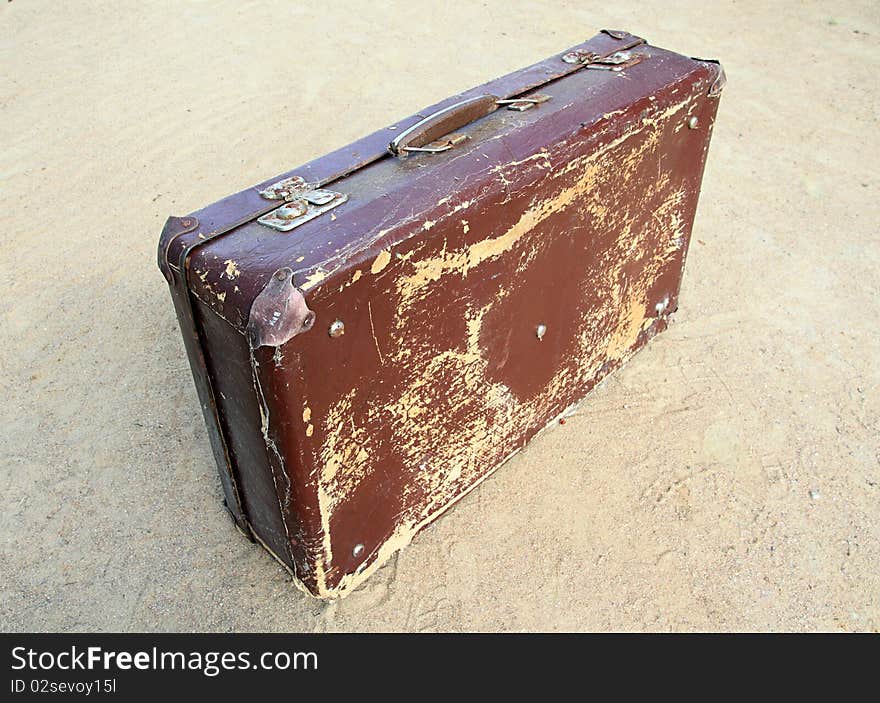 Old valise on yellow sand