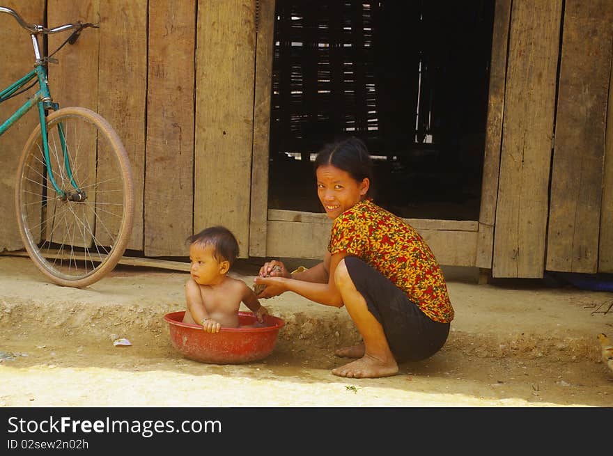 Female Thay giving bath to her child outside her home. Female Thay giving bath to her child outside her home.